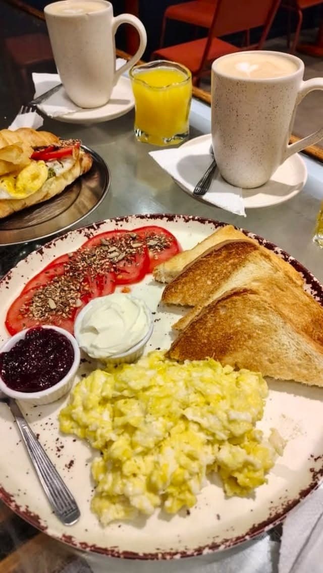 Desayuno completo con lattes, sandwich, tostadas y jugo de naranja