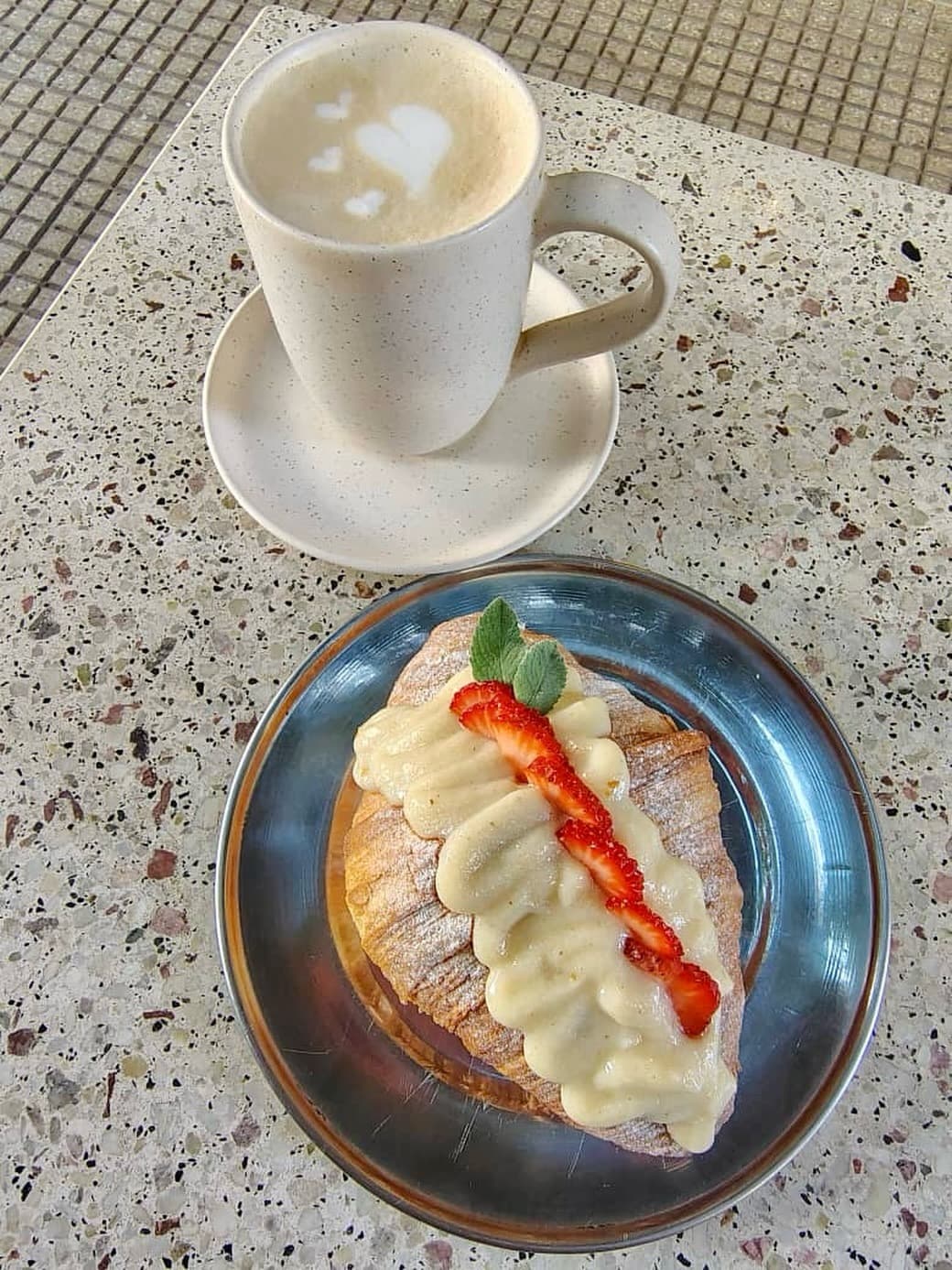 Latte con arte en forma de corazón y pastelería con frutilla