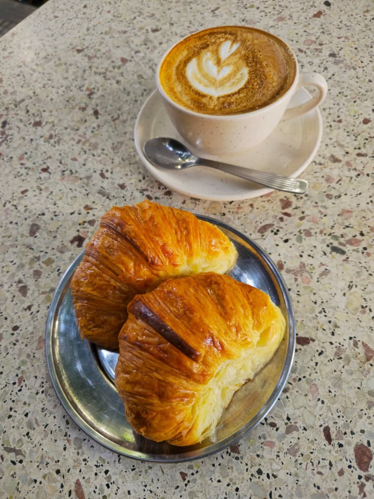 Latte con dos croissants en mesa de mármol