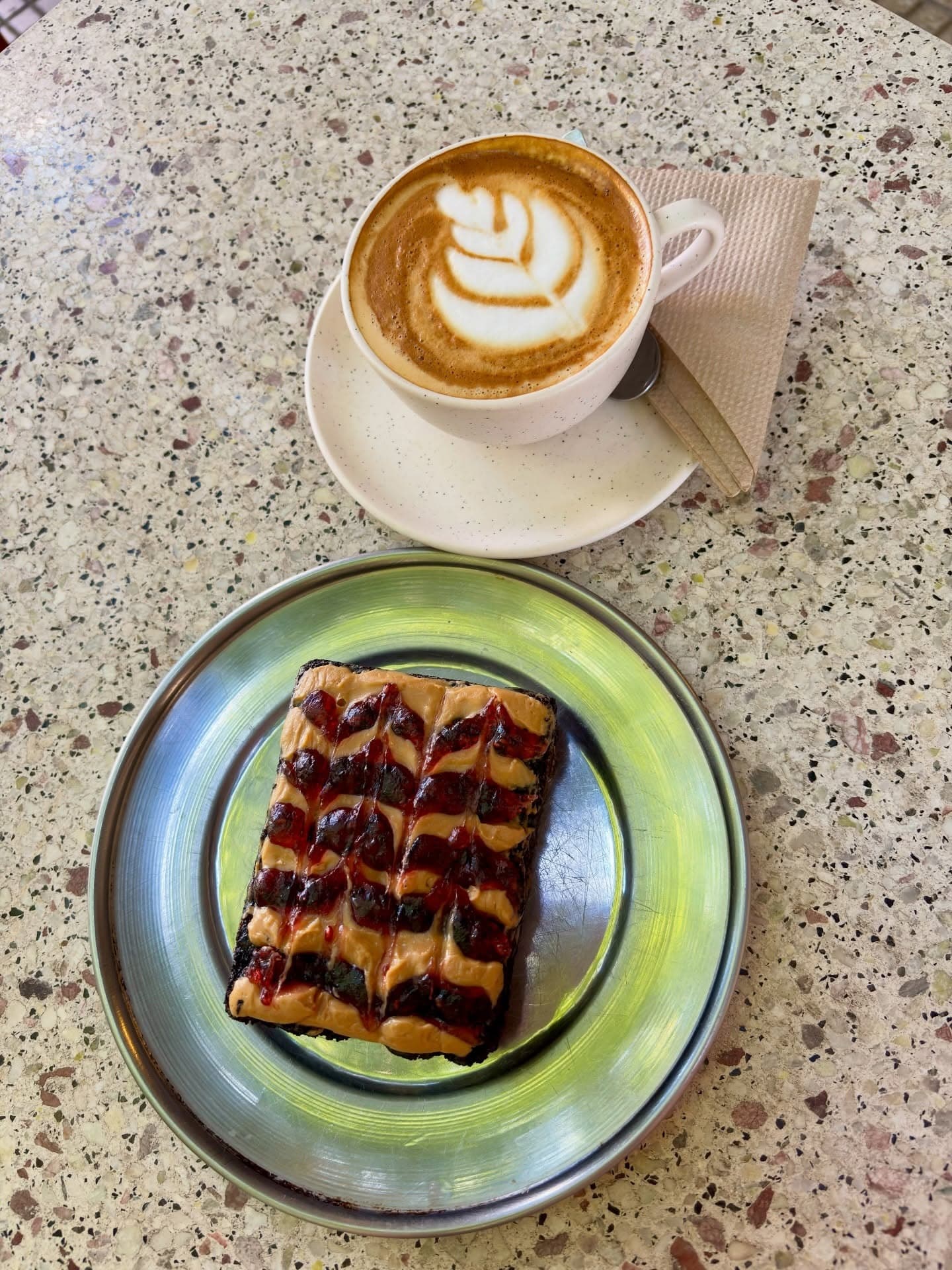 Pastelería con manteca de maní y mermelada junto a un latte